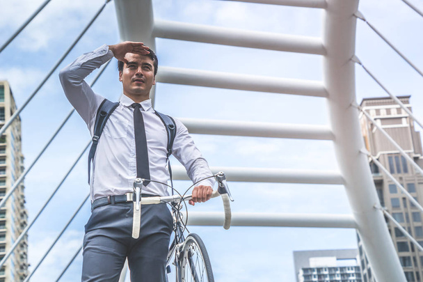 Νεαρός επιχειρηματικός άνθρωπος είναι ιππασία ποδήλατο για να εργαστούν στην πόλη - Φωτογραφία, εικόνα