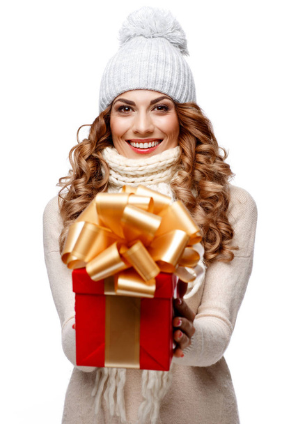 Beautiful young woman in knitted woolen sweater smiling holding gift boxes - 写真・画像