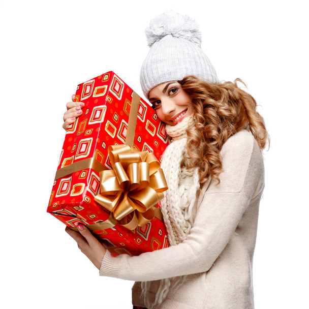 Beautiful young woman in knitted woolen sweater smiling holding gift boxes - Foto, afbeelding
