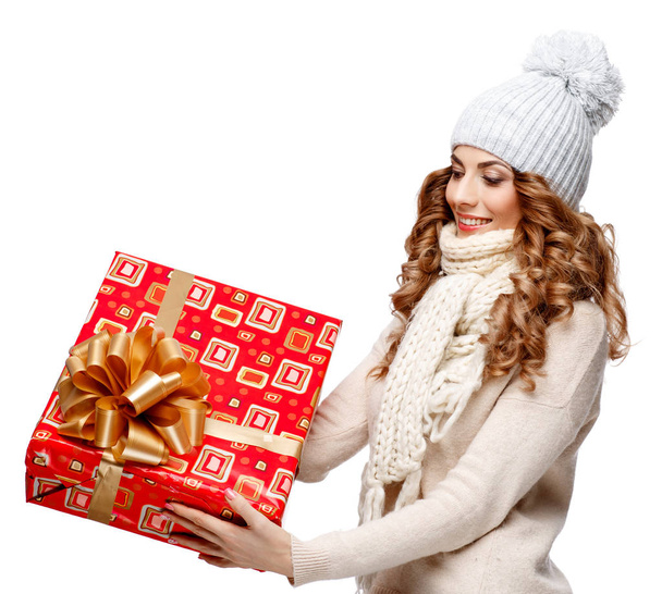 Beautiful young woman in knitted woolen sweater smiling holding gift boxes - Фото, изображение