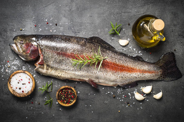 Pesce di salmone crudo intero con ingredienti per cotture su nero
. - Foto, immagini