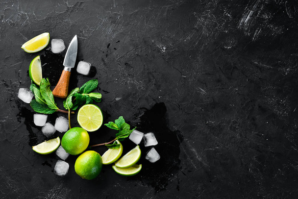 Lime, ice and mint on a black stone background. Top view. Free space for your text. - Фото, изображение
