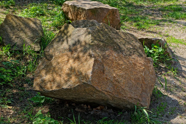 große braune Steine liegen im grünen Gras auf der Natur im Park - Foto, Bild