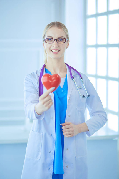 Female doctor with the stethoscope holding heart - Foto, afbeelding