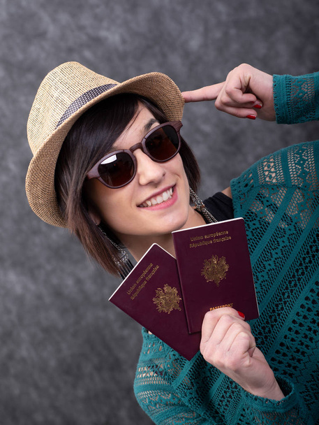 夏の帽子をかぶった若い女性がパスポートを持って - 写真・画像