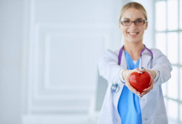 Female doctor with stethoscope holding heart in her arms. Healthcare and cardiology concept in medicine - 写真・画像