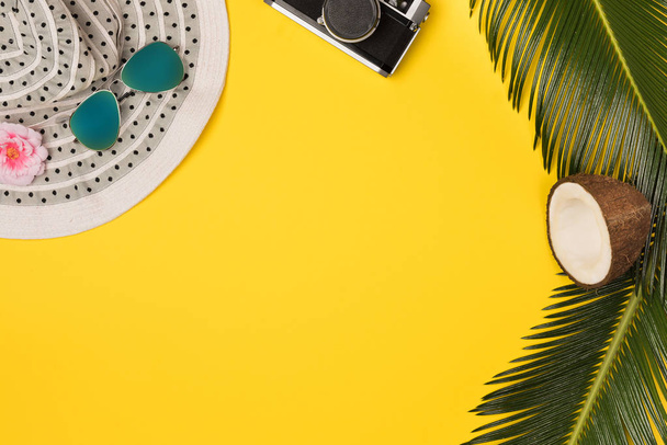 Summer vacation concept. stylish sunglasses, retro photo camera and green palm leaves on yellow background, flat lay. space for text - Фото, зображення