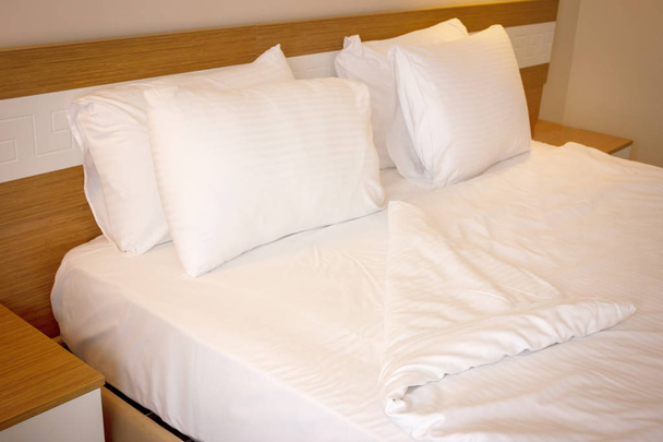 Tweepersoonsbed met wit beddengoed, bereid voor bedtijd slapen - Foto, afbeelding