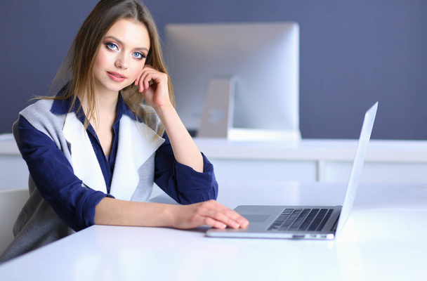 Young confident businesswoman working at office desk and typing with a laptop - Фото, изображение