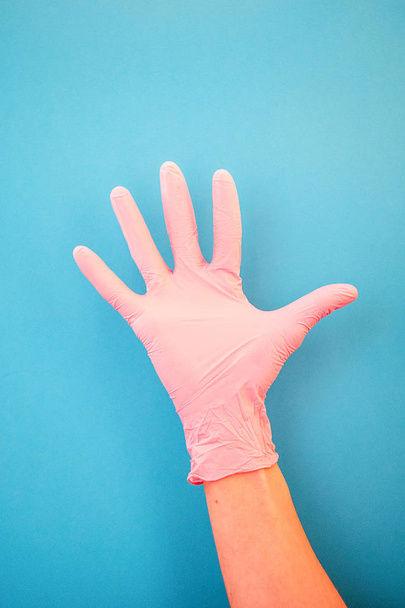Pointing a finger at number five, wearing pink medical gloves, against a blue background. Good habits, vaccination, medical store, pharmacy. - Foto, immagini