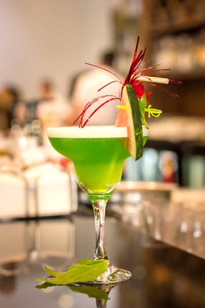 Green alcoholic cocktail with mint in a margarita glass on a bar counter - Zdjęcie, obraz