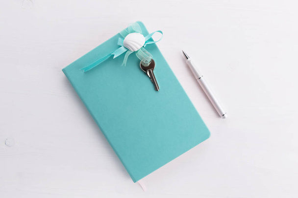 cuaderno de color menta con llaves caseras y un concepto de pluma de cepillar una compra de casa, hipoteca, deuda o préstamo de propiedad o regalo
 - Foto, Imagen