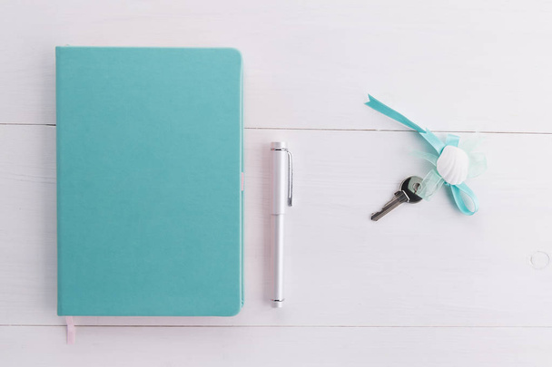 cuaderno de color menta con llaves caseras y un concepto de pluma de cepillar una compra de casa, hipoteca, deuda o préstamo de propiedad o regalo
 - Foto, Imagen