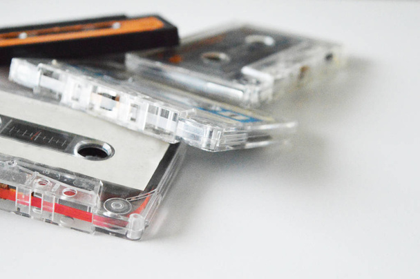 Four retro audio cassettes, white, black, orange, blue on white background. - Photo, Image