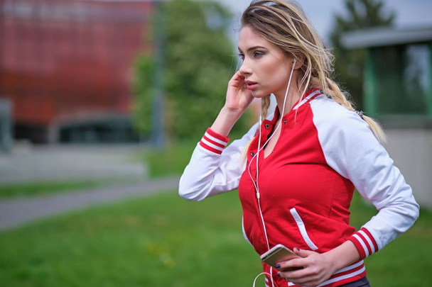 Jonge vrouwelijke atleet is gelet break en luisteren naar muziek durin - Foto, afbeelding