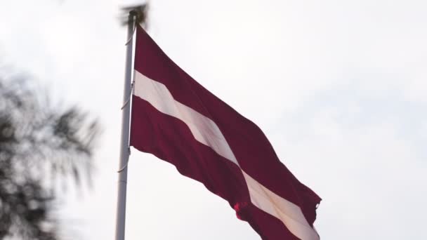 Lotyšská vlajka, která se chvěje ve větru vysoko na obloze během zlaté hodiny slunce v Rize, Velká národní vlajka Lotyšska-dambis AB - Záběry, video