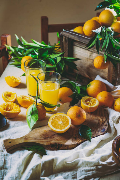 Table with box of fresh orange with orange tree branch and fresh orange juice - Foto, afbeelding