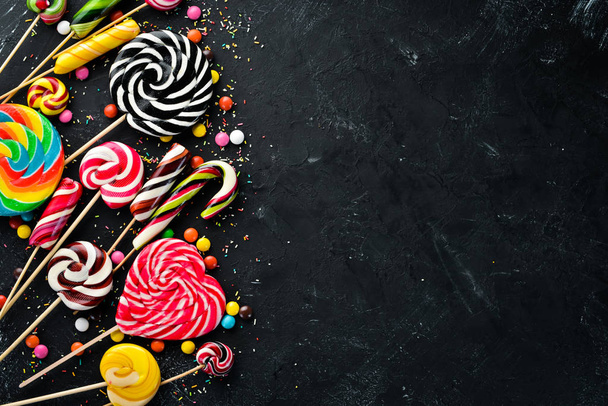 Colorful candies and lollipops. On a black stone background. Top view. free copying space. - Photo, Image