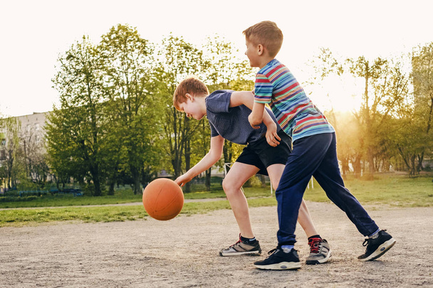 Twee gelukkige jonge jongens spelen basketbal - Foto, afbeelding