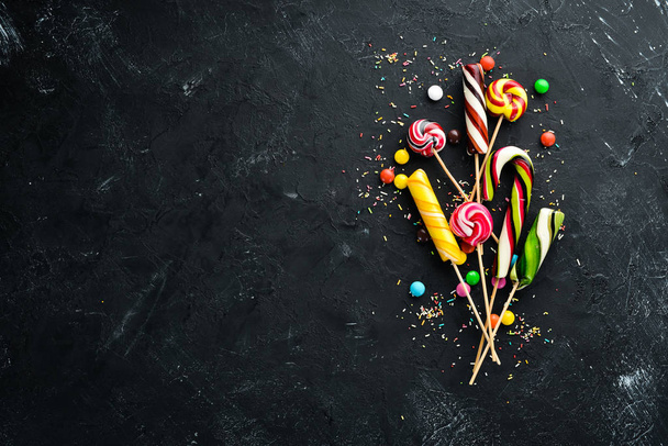 Colorful candies and lollipops. On a black stone background. Top view. free copying space. - Фото, зображення