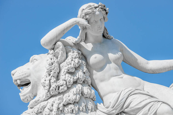 Oude standbeeld sensuele Renaissance tijdperk vrouw leggen op grote leeuw  - Foto, afbeelding