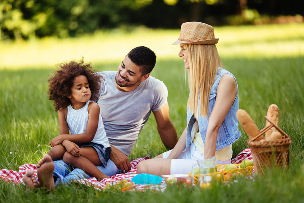 Niña ofendida sentada con los padres en el picnic en la naturaleza
 - Foto, imagen