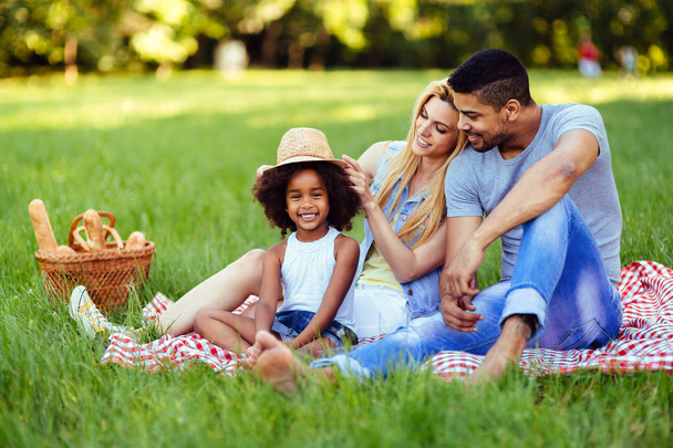 Picture of lovely couple with their daughter having picnic in nature - Фото, зображення