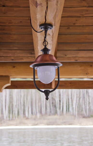 oude lamp hangend aan het houten plafond van het zomerterras - Foto, afbeelding