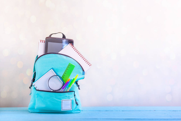 Concept back to school. Full turquoise School Backpack with stationery on table. - Фото, изображение