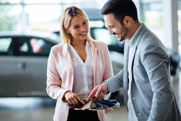 Professional salesperson selling cars at dealership to new buyer - Foto, afbeelding