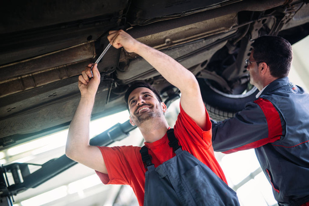 Car mechanics working at automotive service center together - Foto, imagen