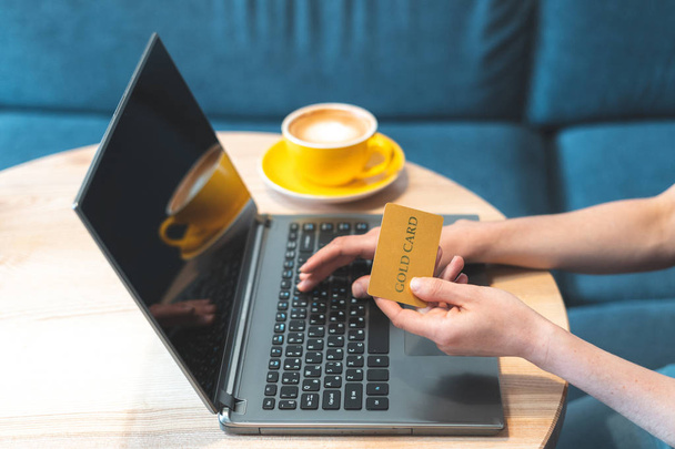Mulher sentada no café e usando laptop com cartão de crédito
 - Foto, Imagem