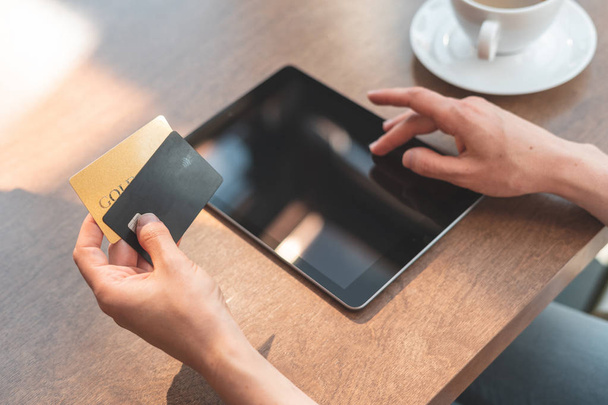 Jovem senhora sentada no café e usando tablet com cartão de crédito para
 - Foto, Imagem