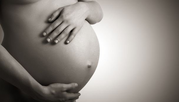 Karın hamile kadın monokrom koyu arka plan üzerinde - Fotoğraf, Görsel