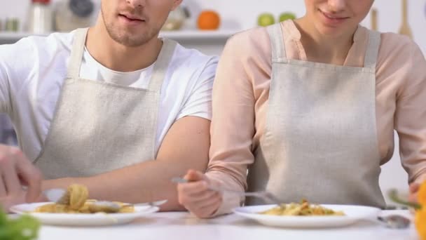 Привабливий чоловік і дружина в фартухах намагаються самостійно зробити спагеті, сімейне приготування їжі
 - Кадри, відео