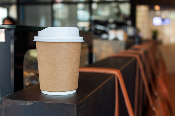 closeup χάρτινο φλιτζάνι ζεστό καφέ στο καφέ με απαλή εστίαση και πάνω από το φως στο παρασκήνιο - Φωτογραφία, εικόνα