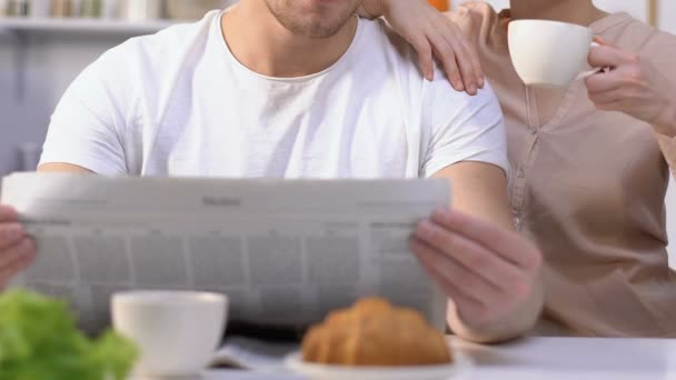 Husband reading morning newspaper, wife drinking coffee admiring life, family - Imágenes, Vídeo