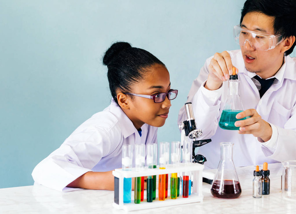 Asian teacher teaching science class to African American student - Foto, afbeelding