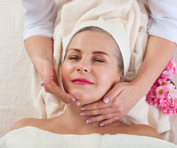 masaje facial en macro spa. Mujer atractiva con ojos cerrados que cuida la piel. Masaje cara enfoque selectivo
. - Foto, Imagen