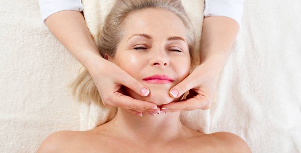 retrato de mulher bonita em ambiente de spa. mulher de meia idade fazendo massagem facial em um salão de spa
 - Foto, Imagem