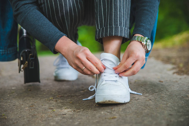 vrouw stropdas veters op sneakers - Foto, afbeelding