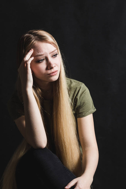 Sad young woman going to cry in a black background - Foto, Imagen