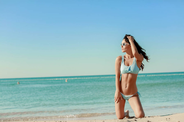 A Beautiful Woman With Sexy Fit Body In Fashion Bikini Relaxing At sea Edge. Female With Long Legs - Φωτογραφία, εικόνα