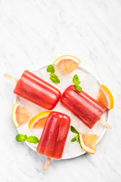 Grapefruit refreshing popsicles on white plate - Valokuva, kuva