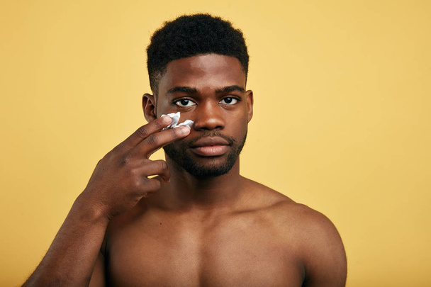 shirtless young brutal african american man applying facial cream - Foto, imagen