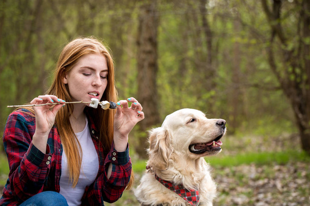Red-haired woman bites roasted marshmallows - Photo, Image
