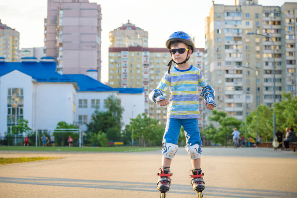 Um rapazinho a andar de patins no Verão no Parque. Feliz ch.
 - Foto, Imagem
