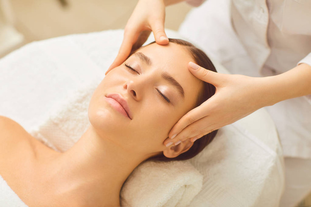 Beautiful girl has a facial massage in a beauty clinic. - Foto, imagen