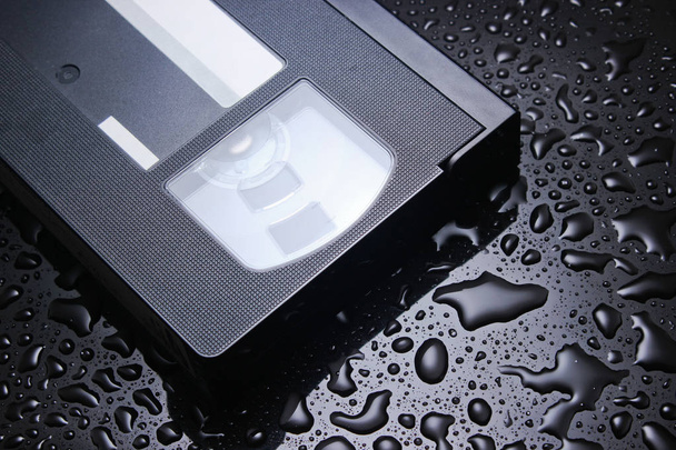 Cassette vidéo rétro sur fond noir avec goutte d'eau
 - Photo, image