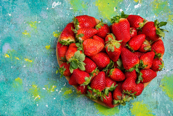 Heart shape strawberries on wooden colorful table, love for fres - 写真・画像